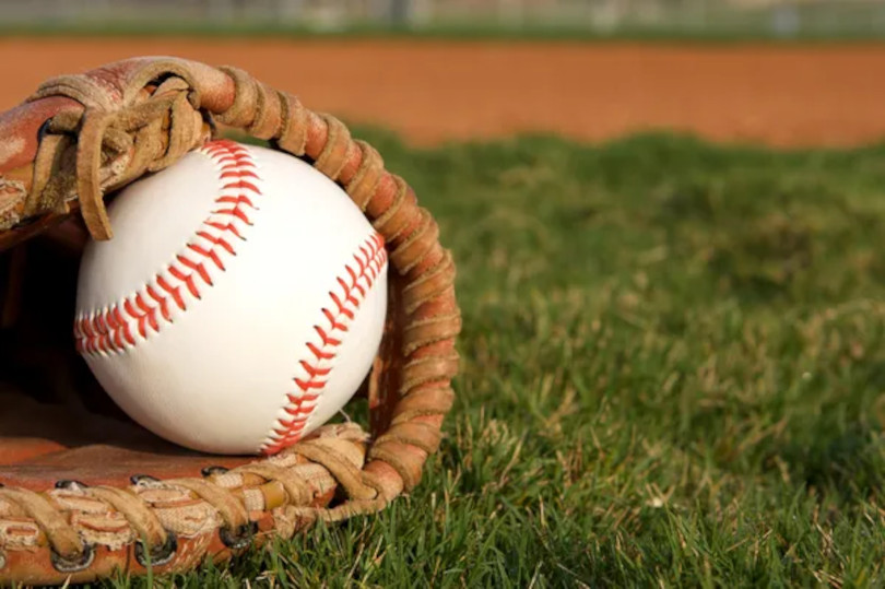 A baseball in a catchers mitt on the grass.