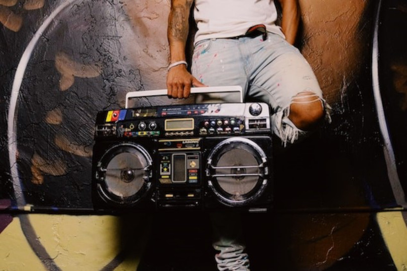 A man sitting on the ground with a boom box.