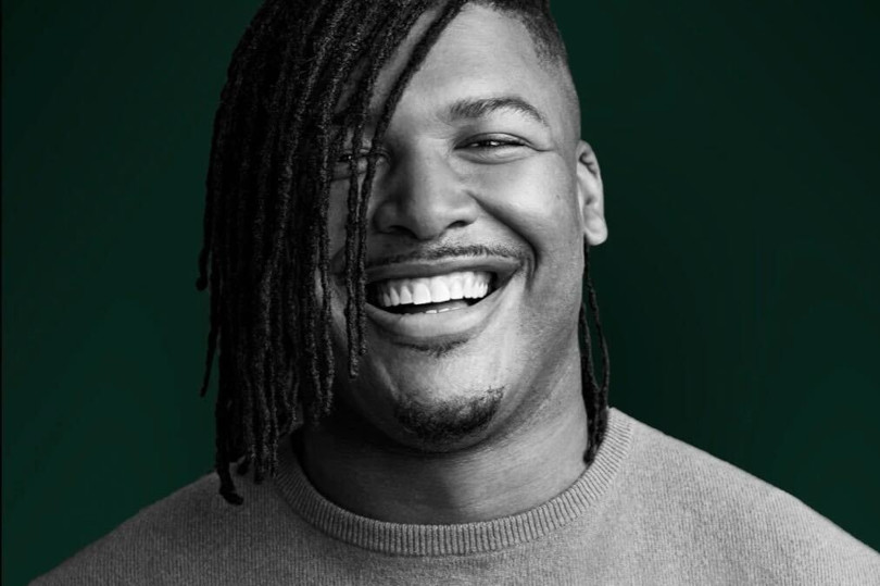 A man with dreadlocks is smiling for the camera.