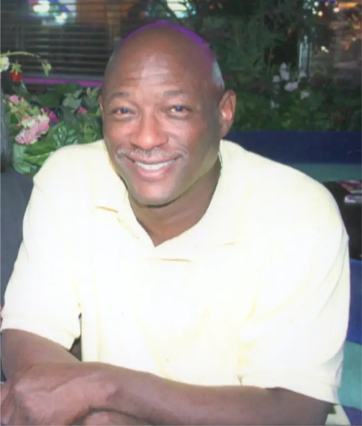 Smiling man in a light yellow shirt.