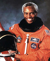 Smiling astronaut in orange flight suit.