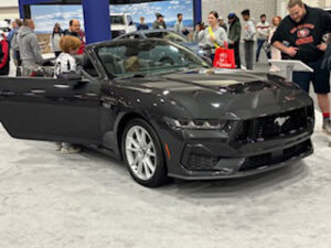 Black Mustang convertible at car show.