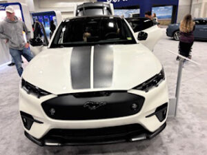 White Mustang EV with black accents displayed indoors.