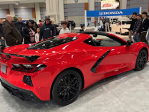 Red sports car with onlookers at event.