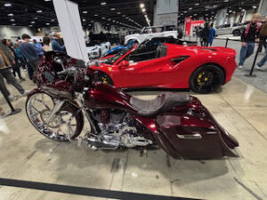 Custom motorcycle beside a red sports car.