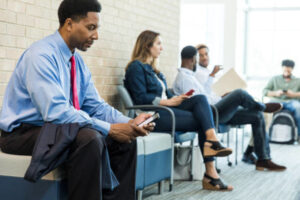 People waiting in a lobby, using phones.