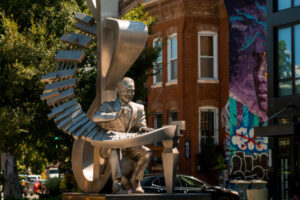 Musician statue in urban neighborhood setting.