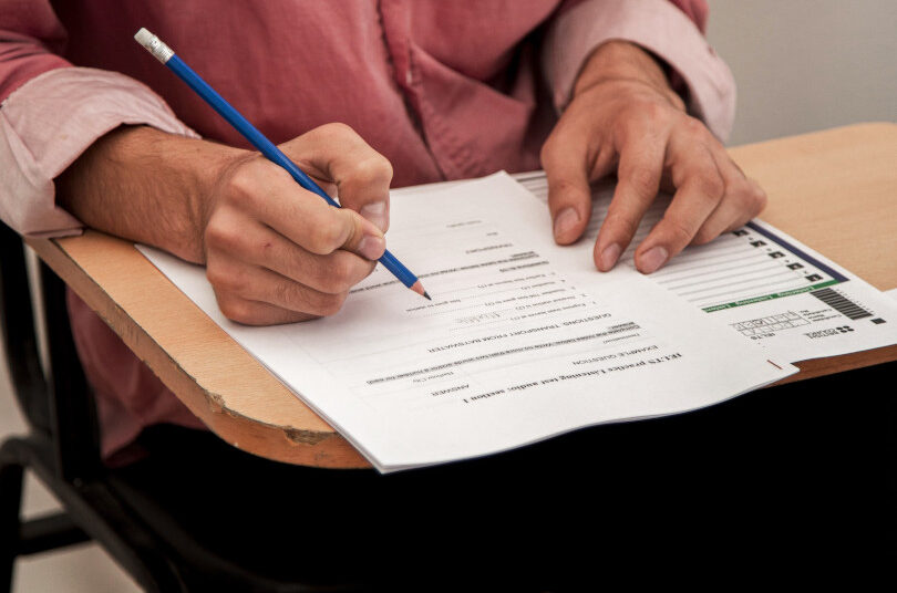 Person writing on paper at desk.