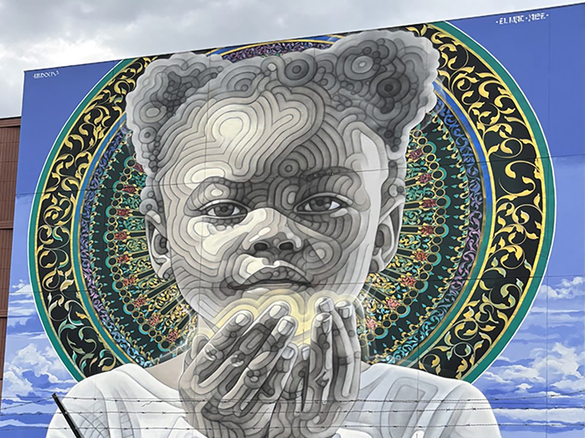 Mural of a thoughtful child with hands near face, featuring intricate patterns behind.